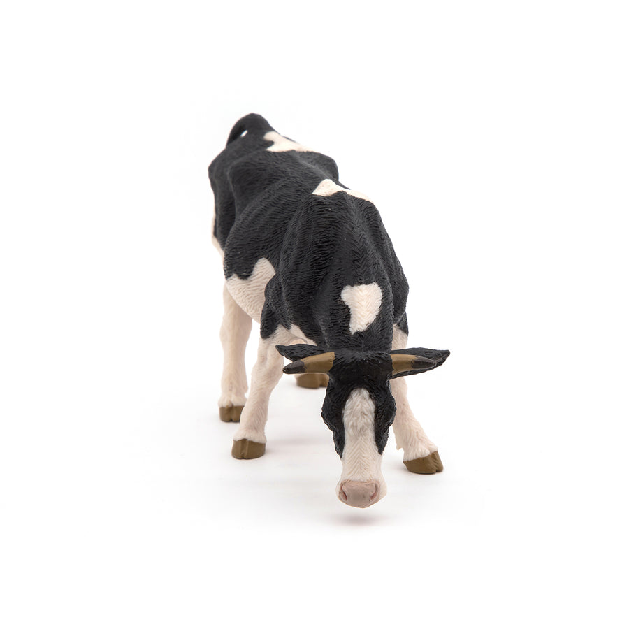 Black and white cow grazing figurine