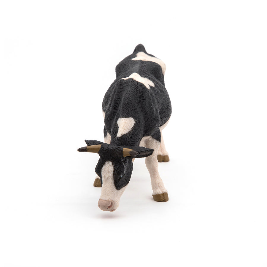Black and white cow grazing figurine