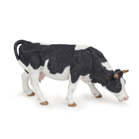 Black and white cow grazing figurine