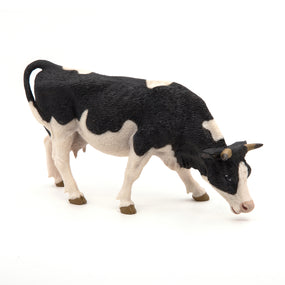 Black and white cow grazing figurine